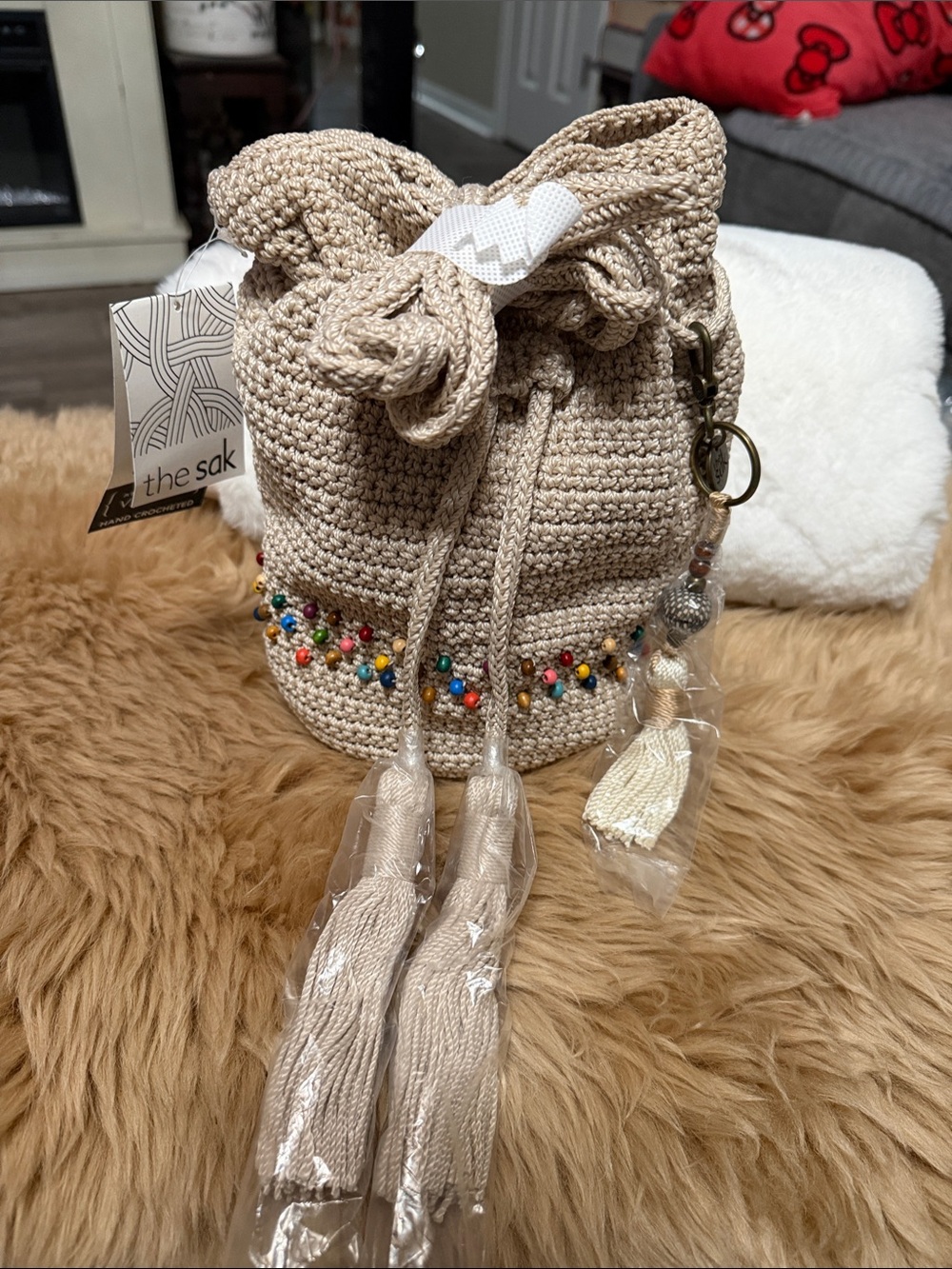 The Sak Beige Crochet Bucket Bag with Multicolor Bead Trim and Tassels